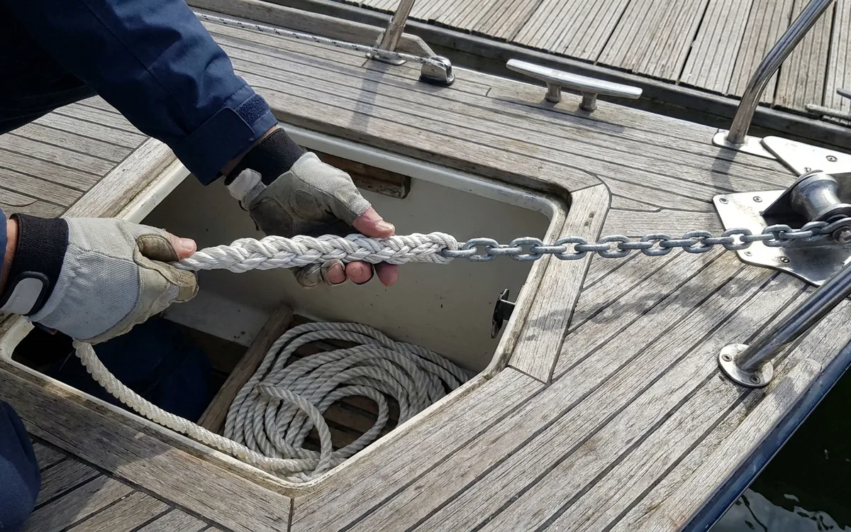 Gloved hands connect 8mm anchor chain to 14mm octoplait warp at the bow locker.
