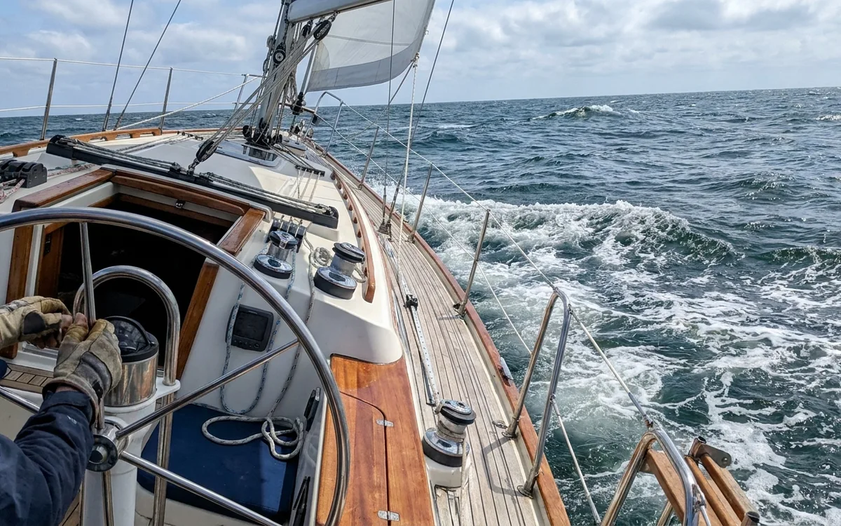 Hands turn the helm to point the bow toward short chop, moving the stern away from the waves.