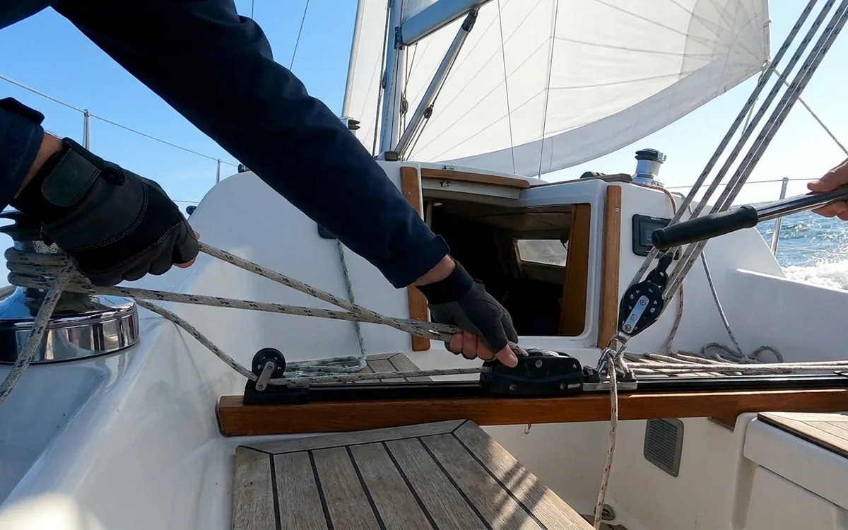 A solo sailor adjusts the Dufour 325 GL mainsheet traveller while holding a steady upwind course.