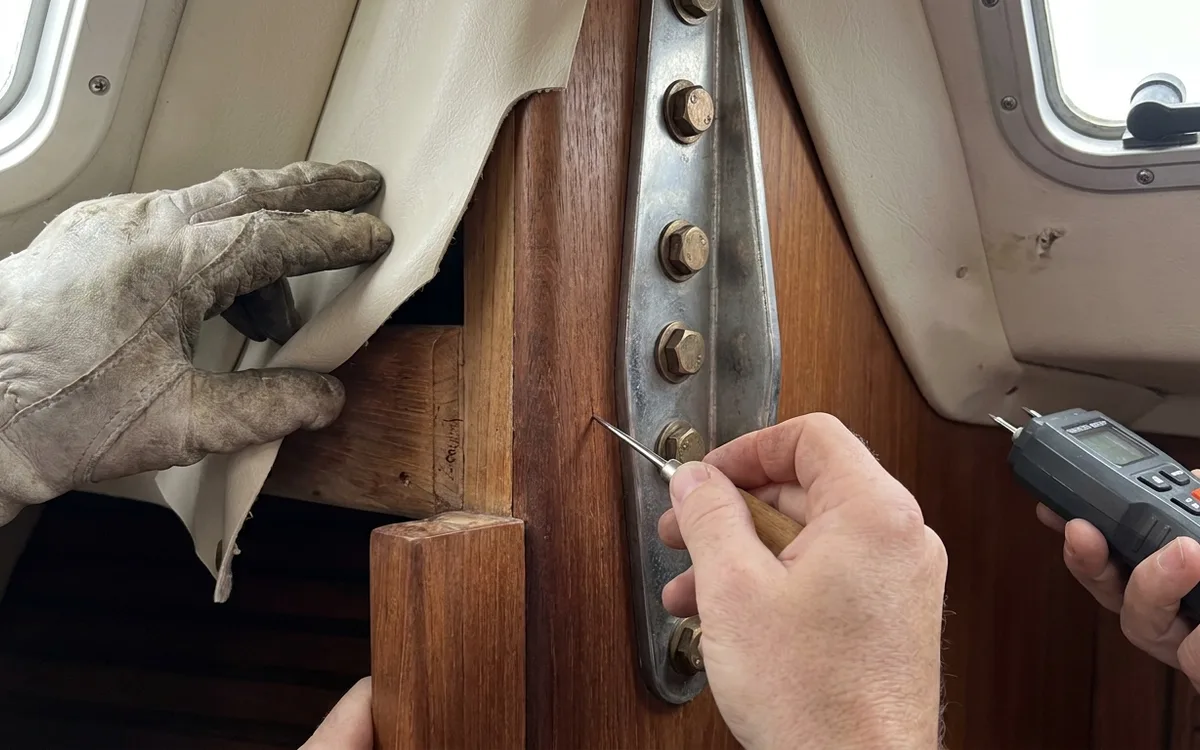 Hands inspect timber and cabin lining beside a Hallberg-Rassy 42 chainplate for damp or softness.