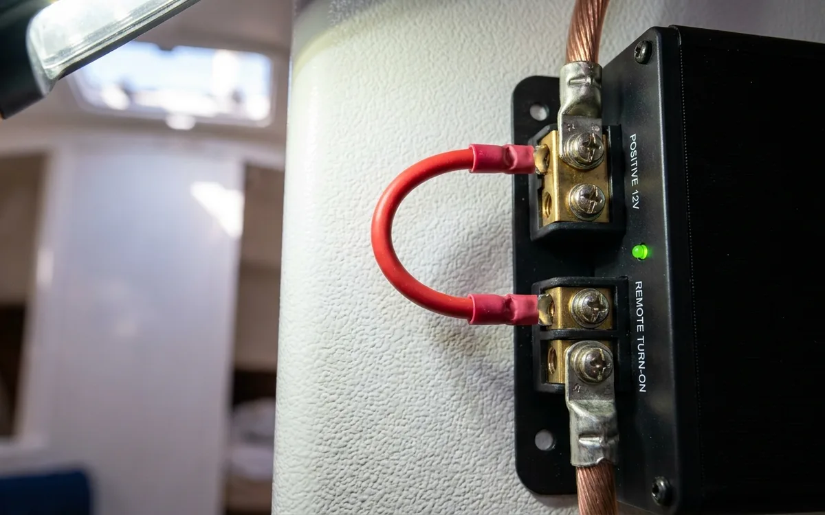 Close-up of a short jumper wire bridging the positive power and remote turn-on terminals on a marine amplifier.