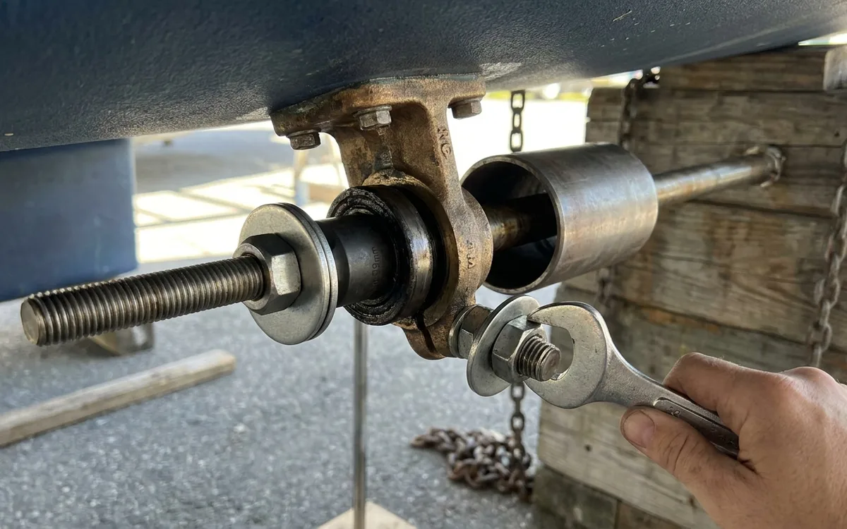 A wrench tightens an M12 rod puller, pressing the old cutless bearing into a receiver tube.