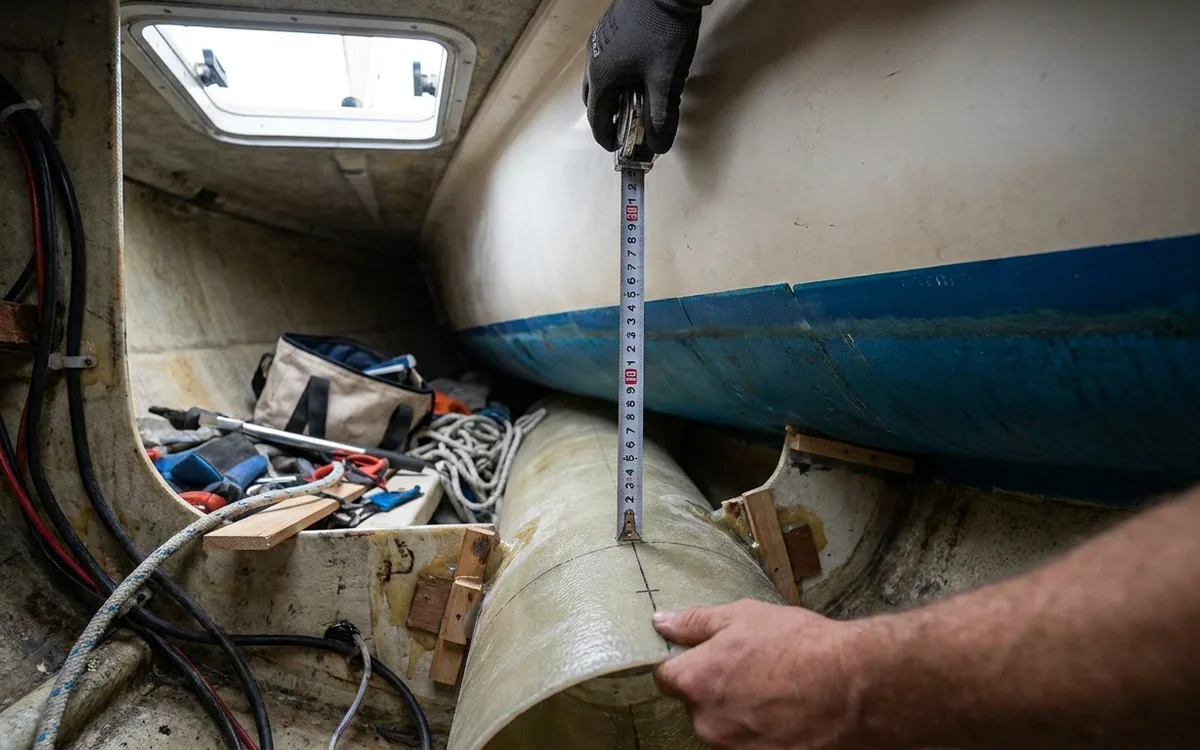 Hands measure from the waterline to a proposed bow thruster tunnel to check its immersion depth.