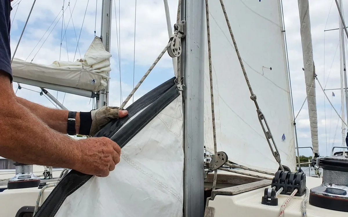 Hands hoist the Nauticat 33’s mizzen, feeding its luff slides into the aft mast track.